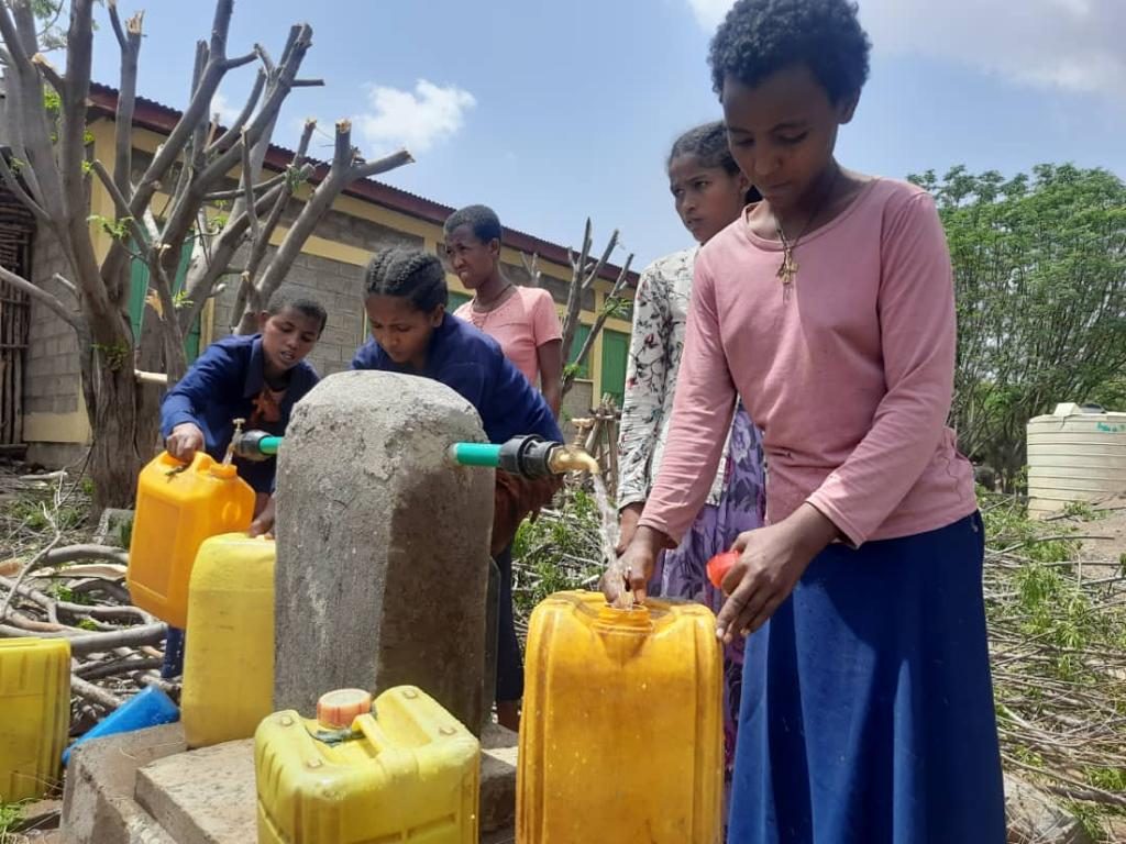 Schoolgirls filling jerry cans with clean water at the new tap