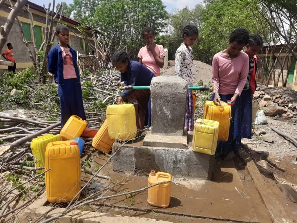 Six girls gathered to fill water containers at the school tap